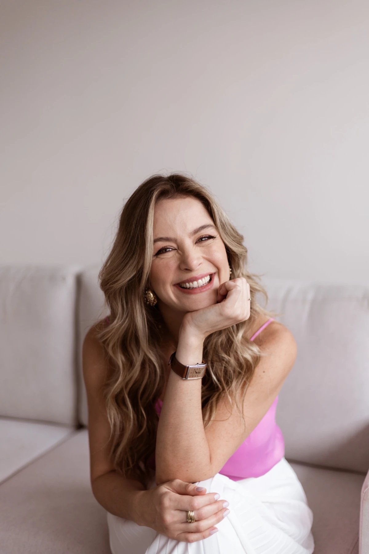 Dra. Aline Casteletti sorrindo, sentada em um ambiente claro